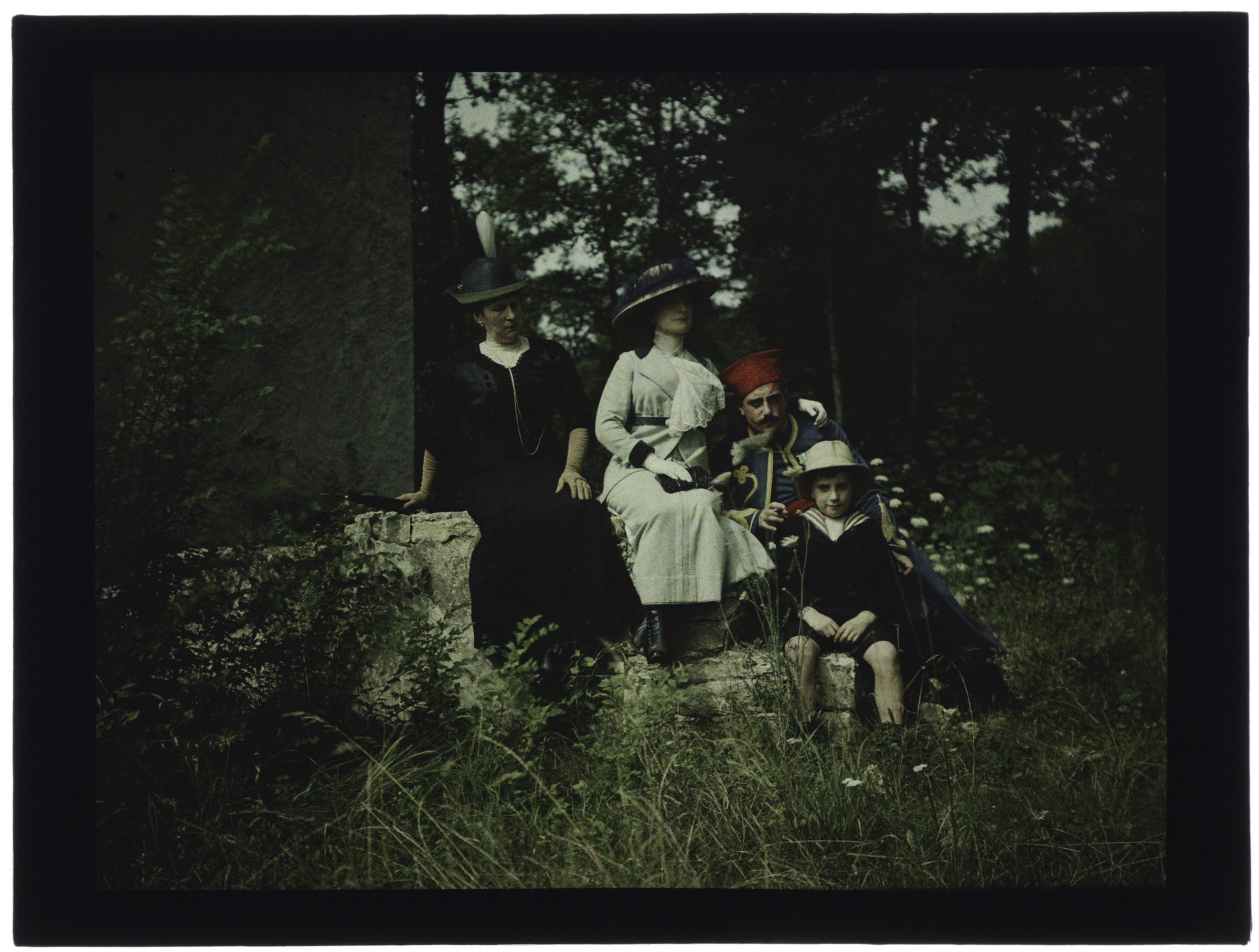 Deux femmes, un soldat et un enfant en costume marin dans la forêt ou les champs