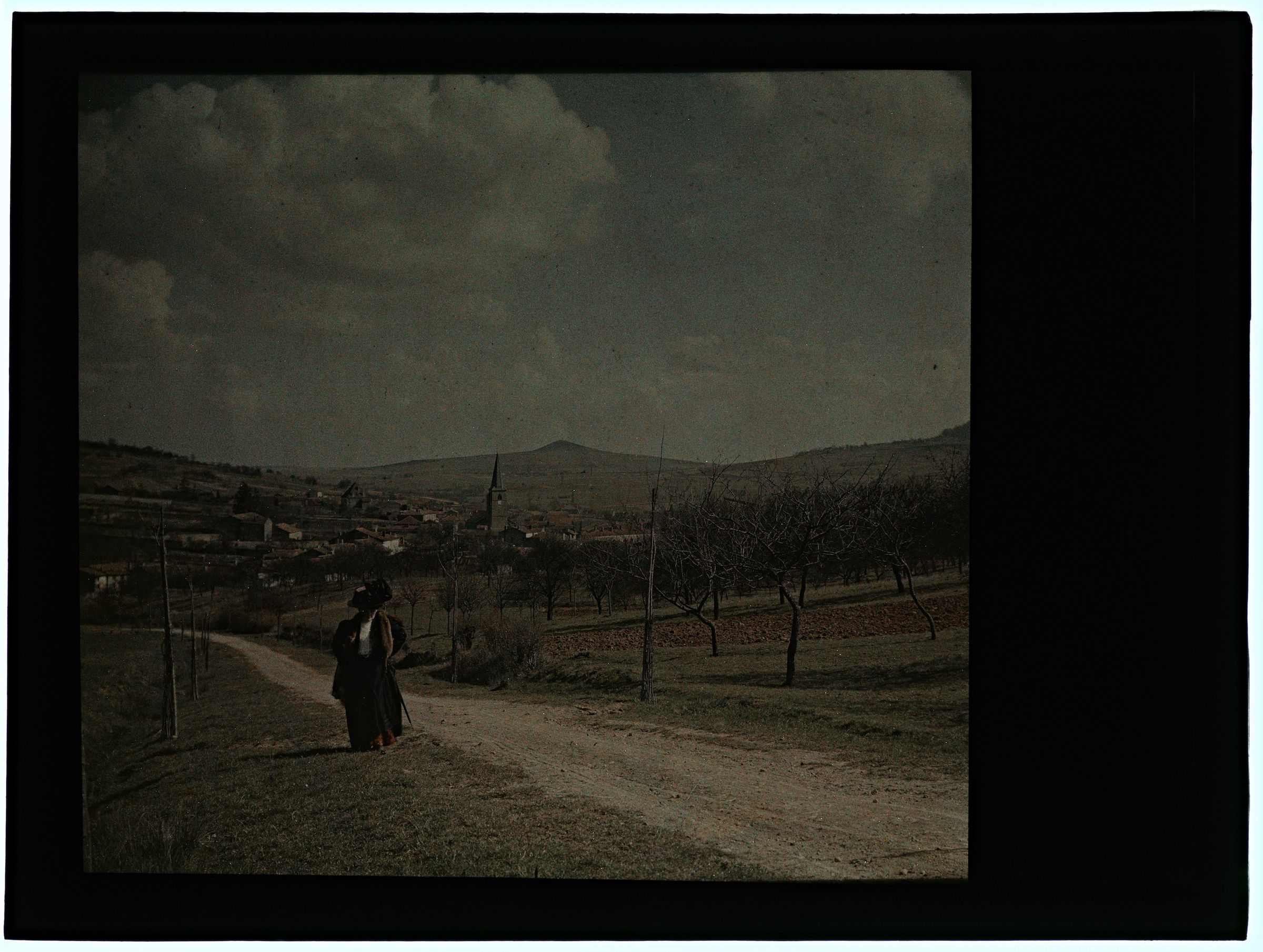 Femme dans la campagne avec village en arrière plan