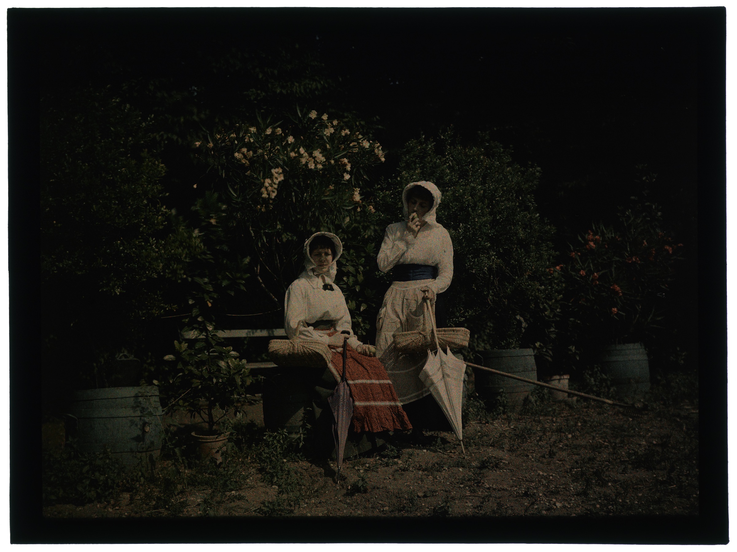 Deux femmes en hâlette au jardin fleuri
